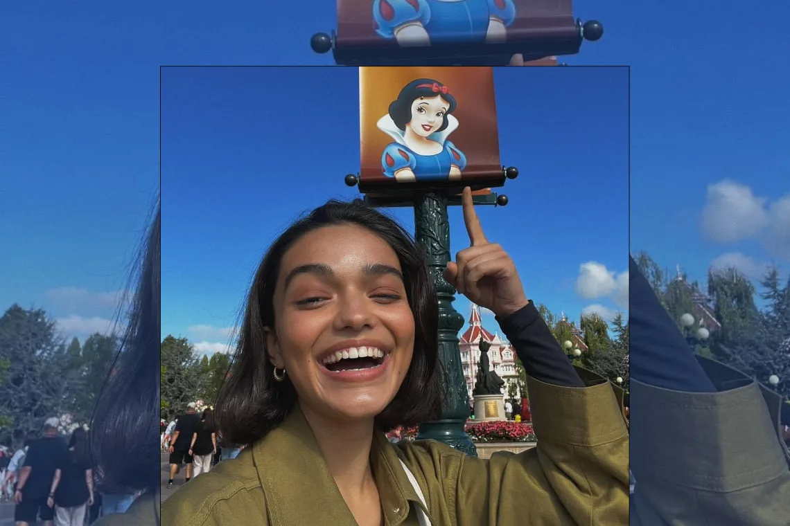 Actrice Rachel Zegler nabij een reclamebord met een afbeelding van de originele prinses. Foto X