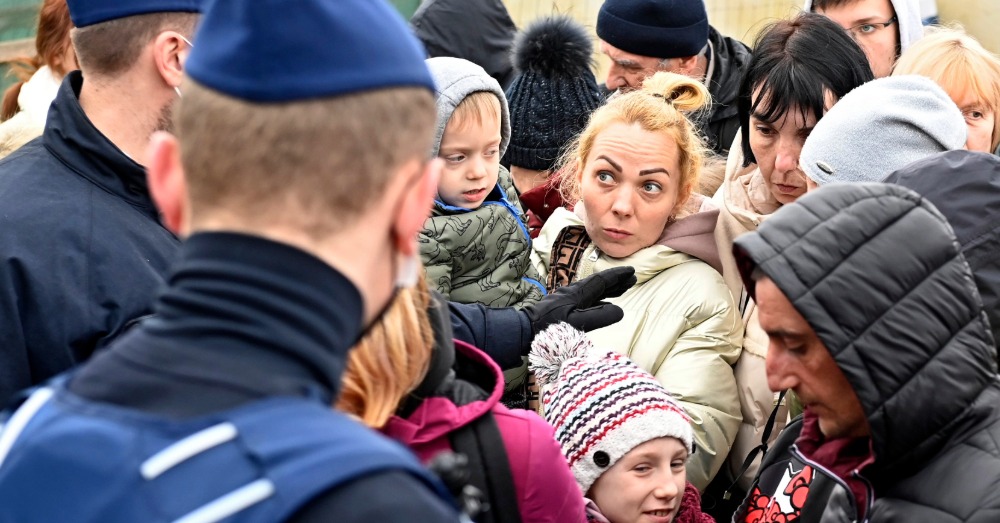 Vrouwen en kinderen staan tegenover politieagenten bij de opvang van ontheemden.